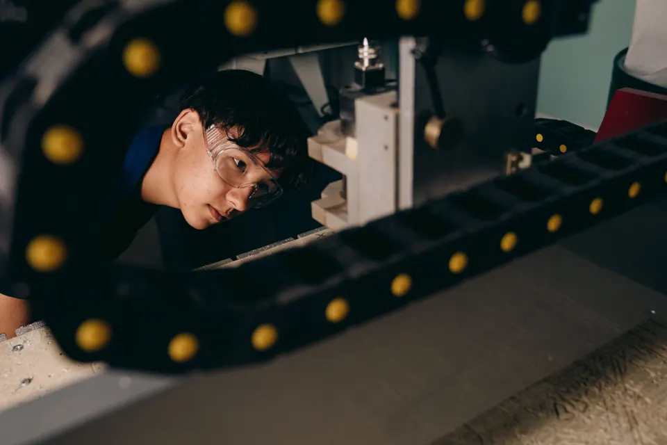 Techniker mit Schutzbrille prüft eine Maschine in der Fertigung