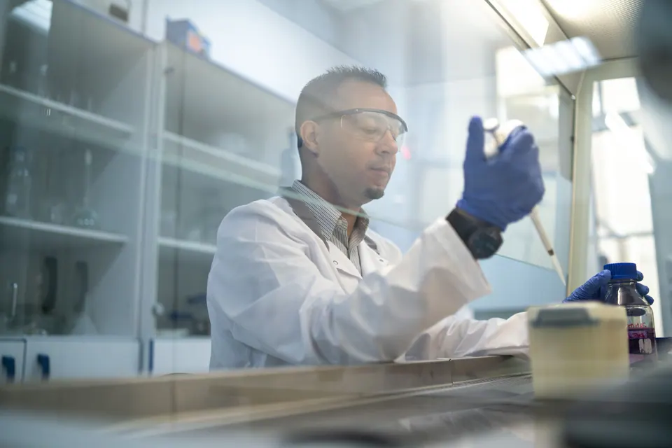 Wissenschaftler mit Schutzbrille arbeitet an einer Laborbank